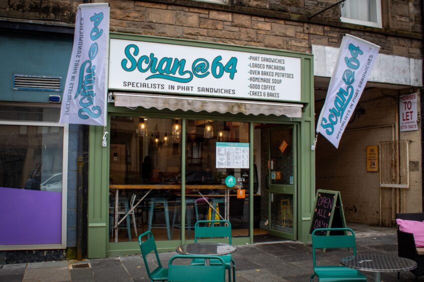 Green Scran@64 cafe exterior in Stirling, with outdoor tables and chairs visible in the foreground.