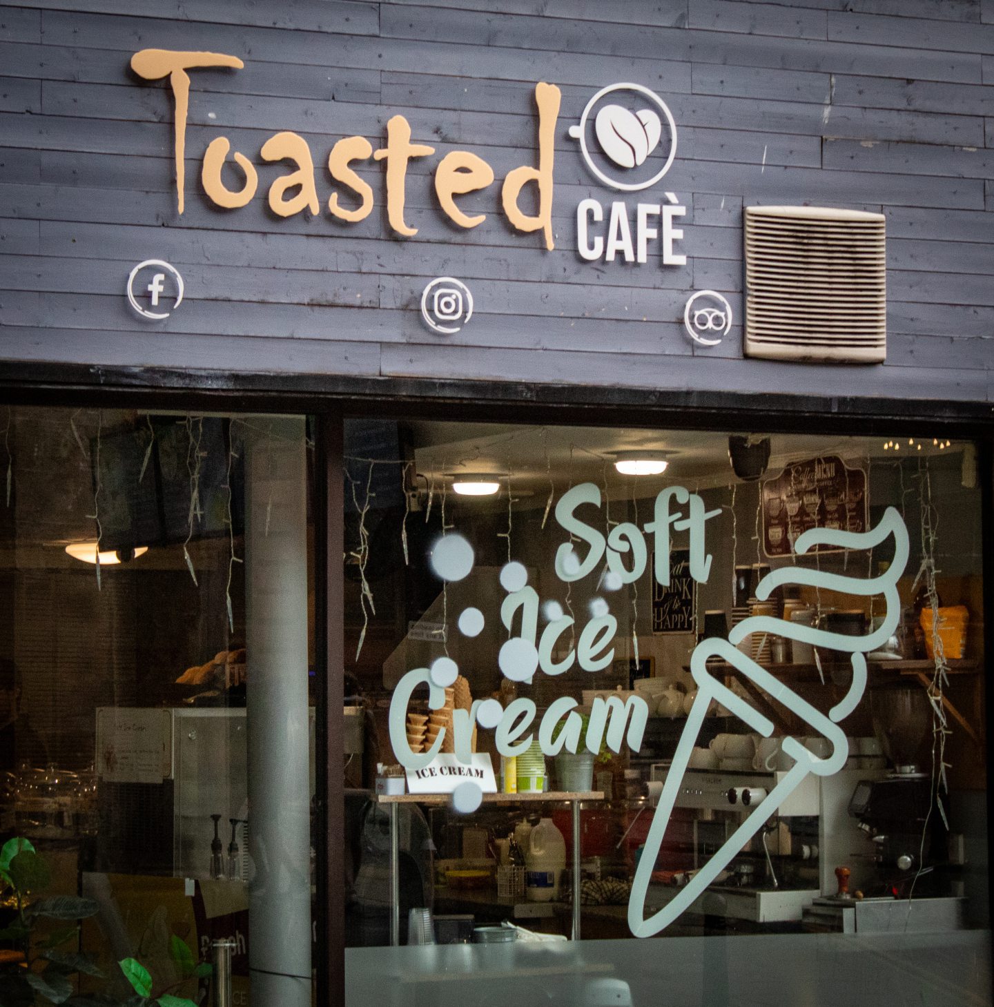 Close-up of Toasted cafe's sign and front window with advertisement for soft ice cream, in Stirling city centre