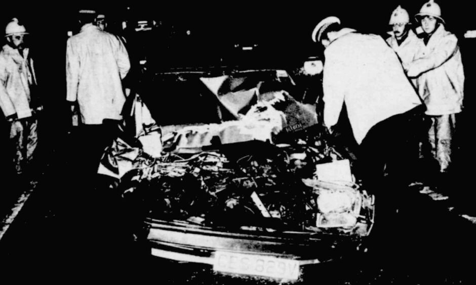 Police and firefighters beside the car wreckage following the accident in 1982. 