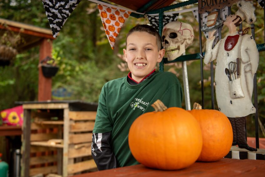 Oscar Smiling next to a pumpkin and some Halloween decorations.