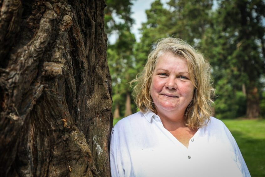 Fiona Ross leaning against Redwood tree trunk