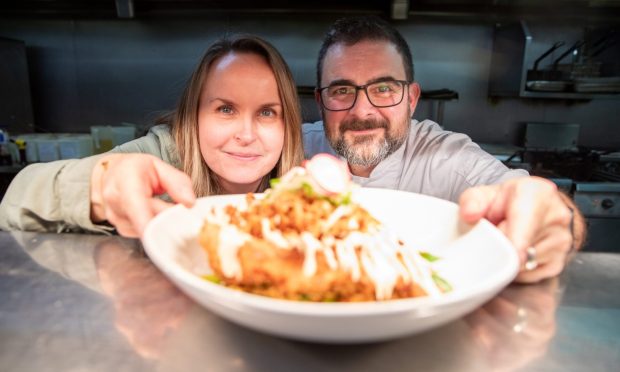 Food and drink writer Rachel with head chef Jesse Spears holding a plate of food at the pass in The Meadowpark's kitchen.