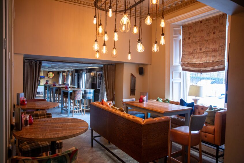 The interior of The Meadowpark restaurant looks cosy and has lots of little lights hanging down to create a warm glow above the bar restaurant style table.