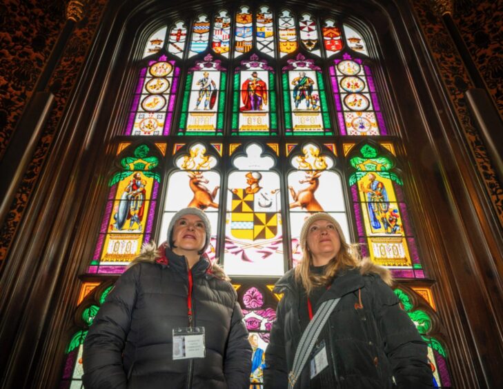 Two women standing in front of ornate stained glass window at Taymouth Castle