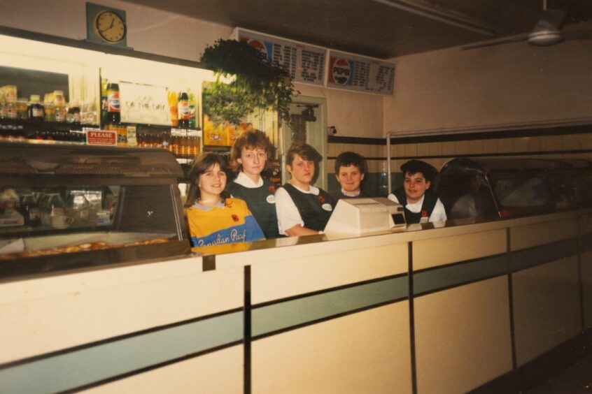 Five girls behind chip shop counter around the 1980s