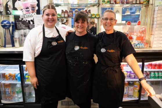 Three women standing in front of fish fryer at Auchterarder chip shop