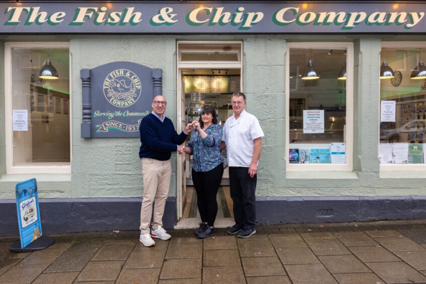 Gillian and Bill Whitelaw on steps of Fish and Chip Company, Auchterarder, handing over keys to Fergus Watson