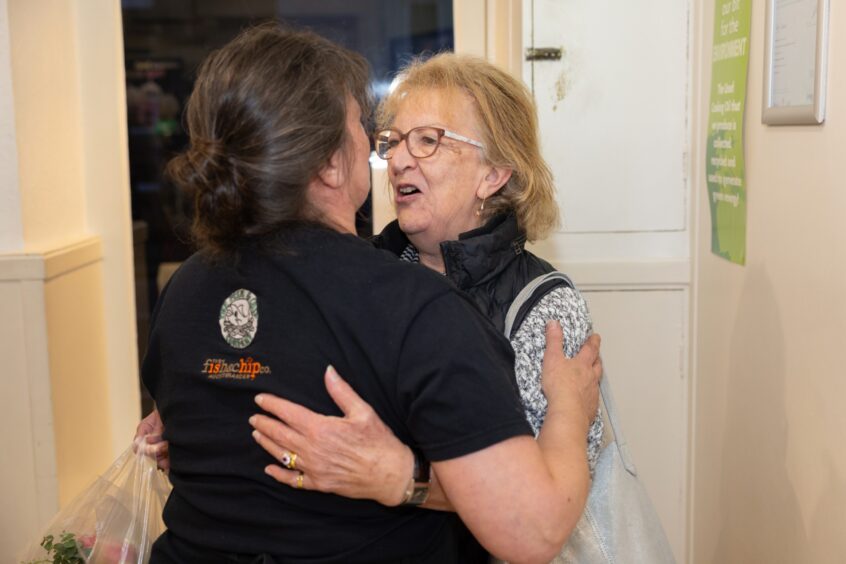 Gillian Whitelaw hugging older woman in chip shop