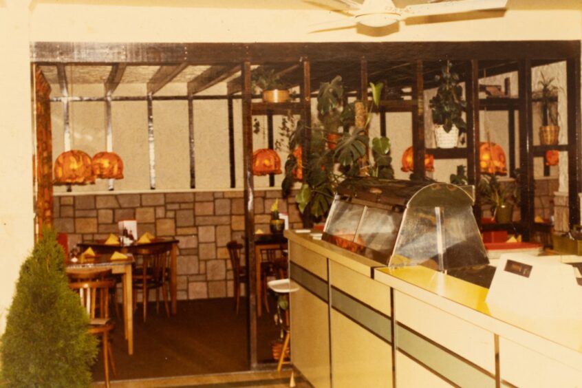 Photo of chip shop with adjoining seating area in 1970s colours and styles.