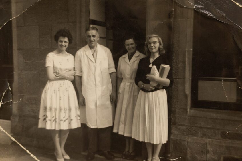 Black and white photo of four people in 1950s styles outside Auchterarder chip shop