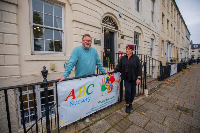 Alan Morgan and Donna Gibson standing next to ABC Nursery banner on railings outside nursery on Rose Terrace, perth.