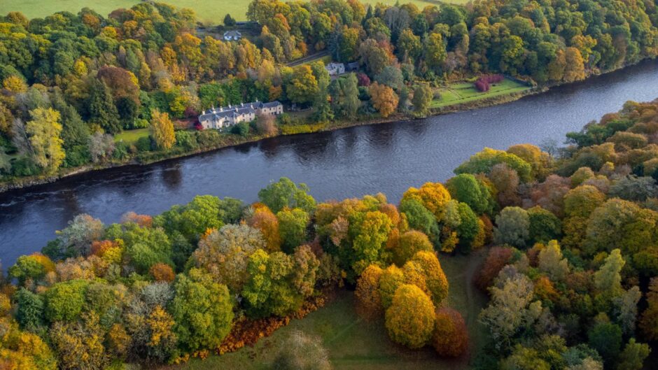 The River Tay near Dunkeld in Perthshire is lined with rich golds and orange autumnal trees 