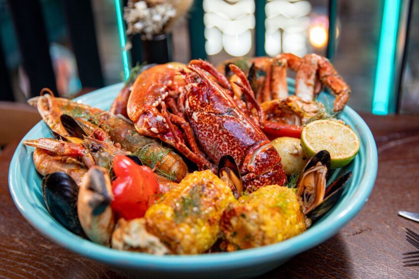 Dune's seafood boil with a selection of shellfish, corn on the cob and red peppers in a blue bowl.