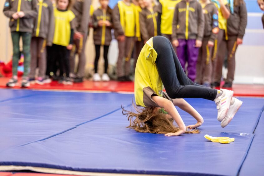 A girl Brownie does a forward roll during the Cheerleading with Dundee Tribe Cheerleaders.