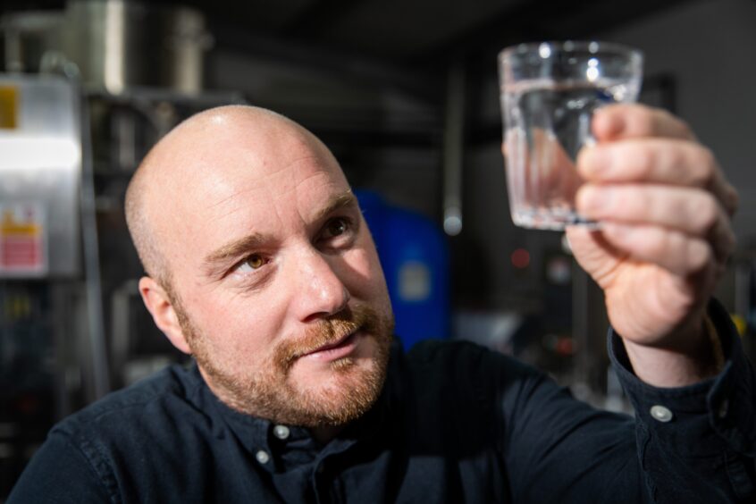 Darren Peattie looking at a fresh glass of his Vivimus water.