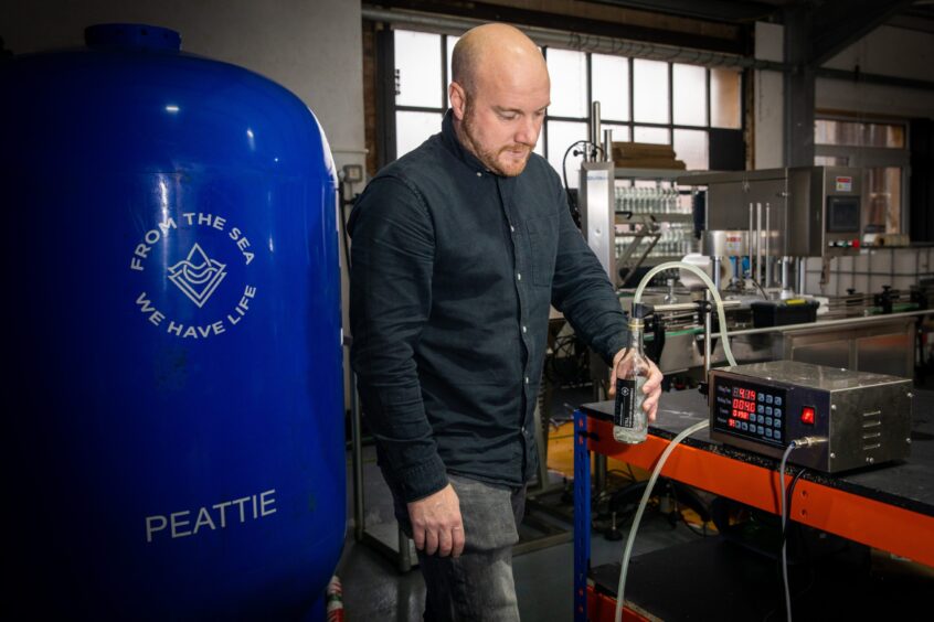 Darren Peattie pouring some of his water from a pipe into a bottle for testing.