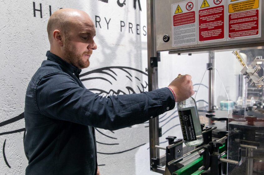 Darren Peattie takes a bottle from the capping machine.