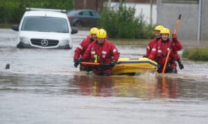 The Coastguard Rescue Team evacuating residents in Brechin, Scotland, as Storm Babet battered the country. Shows four people wading through deep water with an inflatable boat.