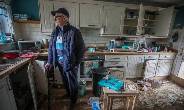 Ian Stewart who lives on River Street, standing last year in his home which was is completely ruined by flood water. Image: Mhairi Edwards/DC Thomson