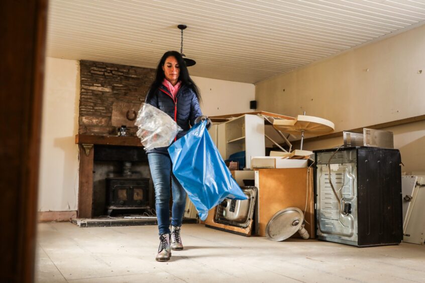 Gayle attempt to clear rubbish from her flood-damaged home in Kinnettles. Image: Mhairi Edwards/DC Thomson.