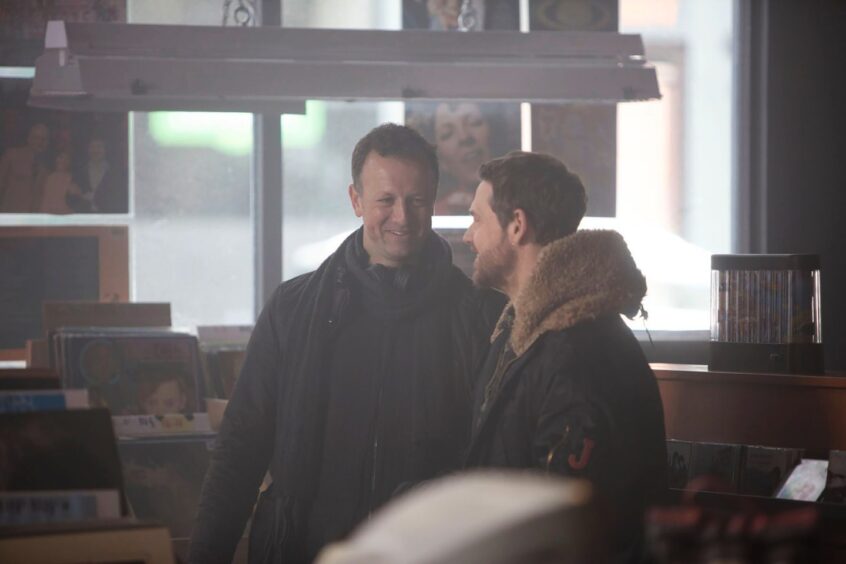 Neil alongside Jamie Sives during a break in shooting in the second-hand record shop. 