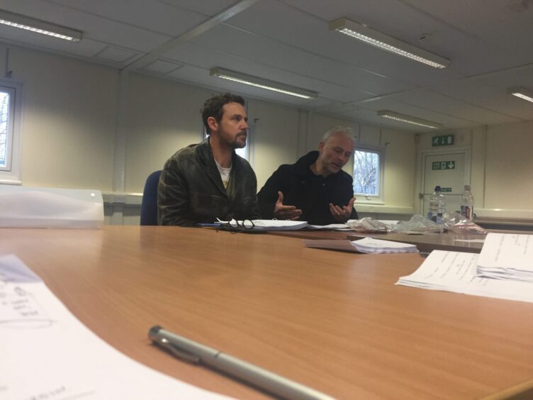 Actors Jamie Sives and Mark Bonnar sitting at a table reading the Guilt script in rehearsal. 