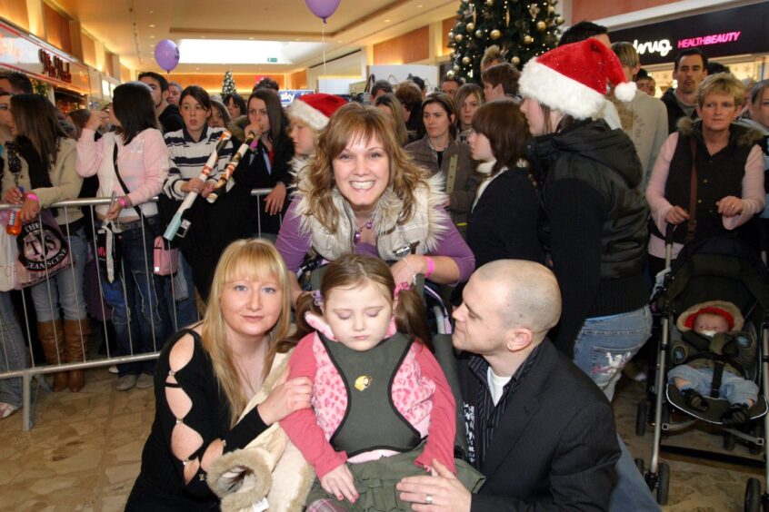 A young girl in a wheelchair gets ready to meet Girls Aloud, as fans gather behind her in the Mercat Shopping Centre