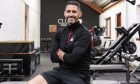 Mike Lindsay sits with his arms folded in front of his gym.