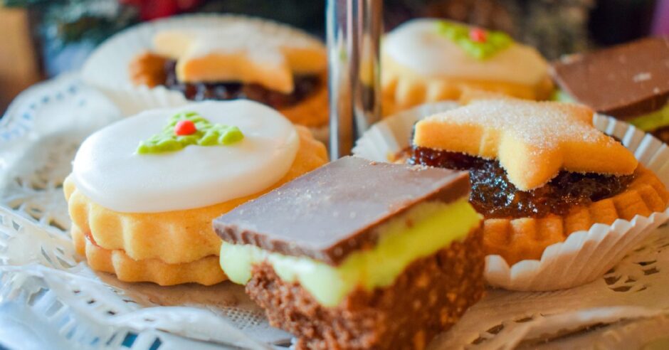 A mint slice, mince pie, Christmas-themed empire biscuit on an afternoon tea stand.