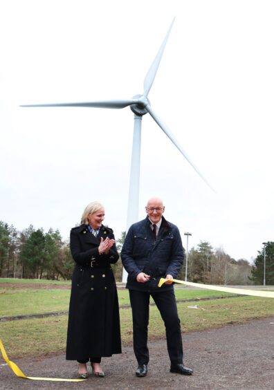 John Swinney cutting ribbon in front of turbine while Amanda Blanc of Aviva claps her hands