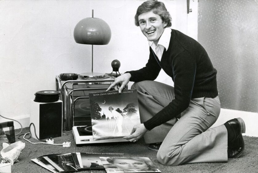 A kneeling Hegarty holds an album as he shows off his record collection at home in October 1978.