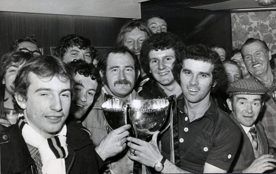 A mobbed Frank Kopel shows off the trophy to United supporters.