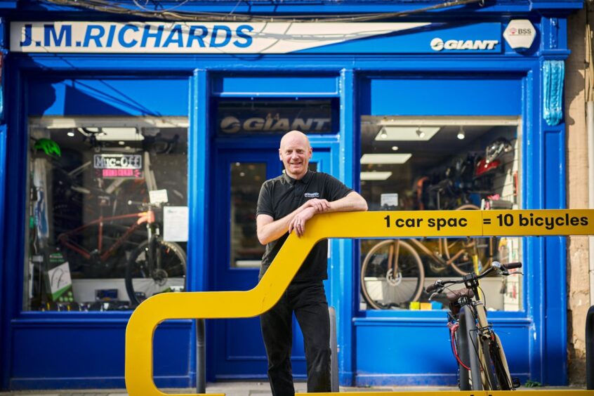 man stands outside the facade of the J.M. Richards bike shop