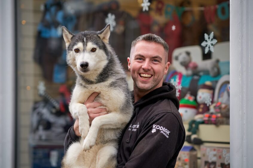 man smiles broadly as he holds a big dog