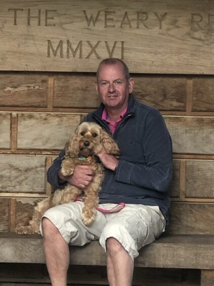 David McCann seated with dog on lap