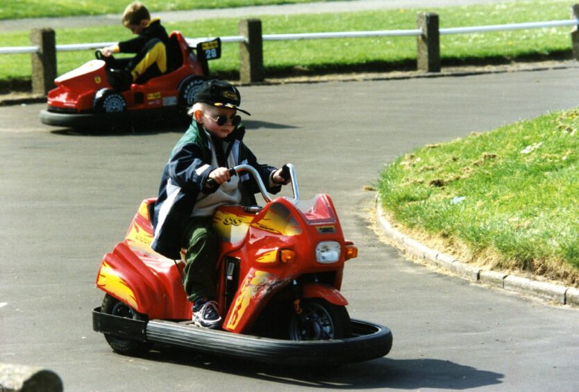 a young boy rides an electric three-wheel bike round a track