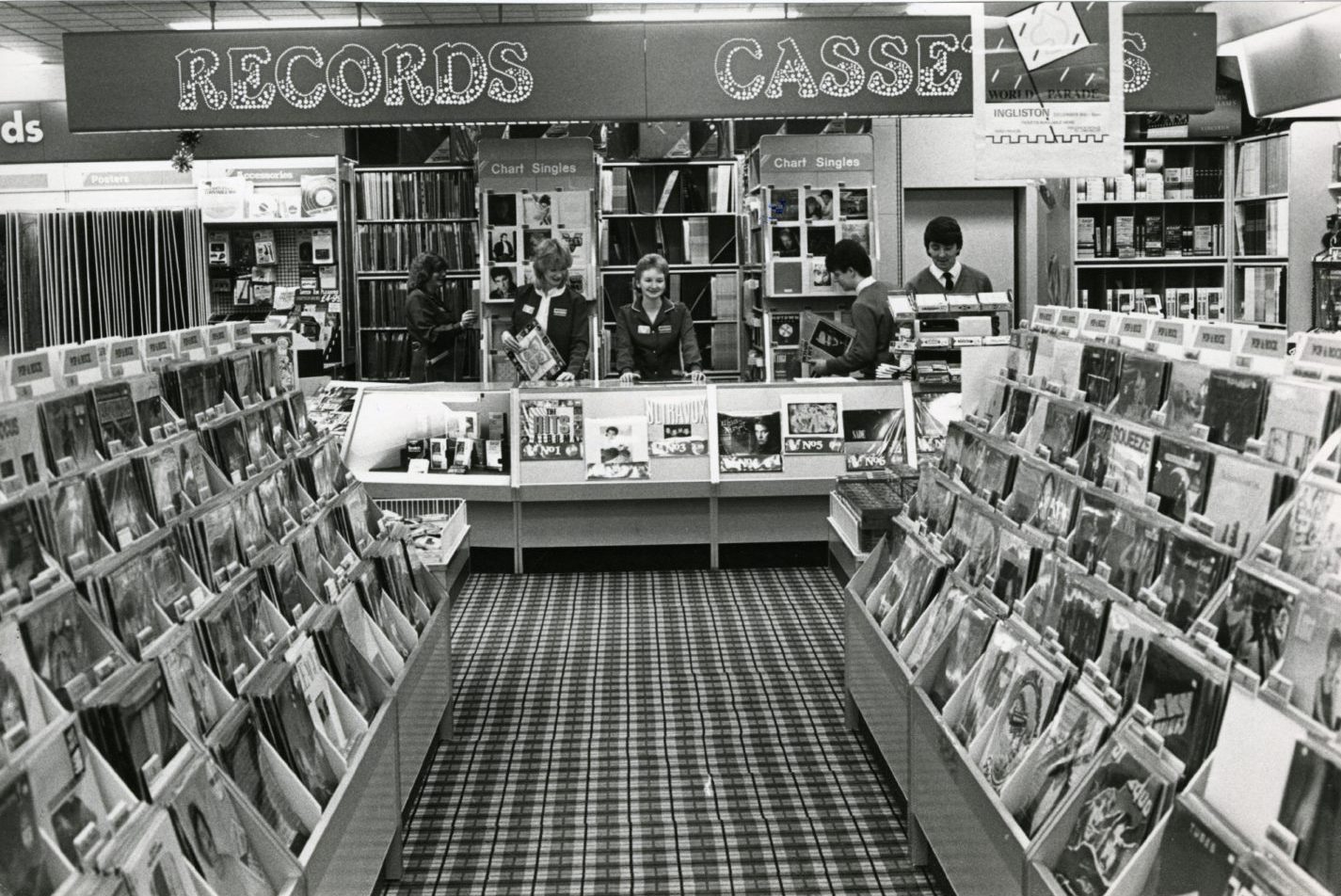 people work behind the counter in the record department at John Menzies in 1984