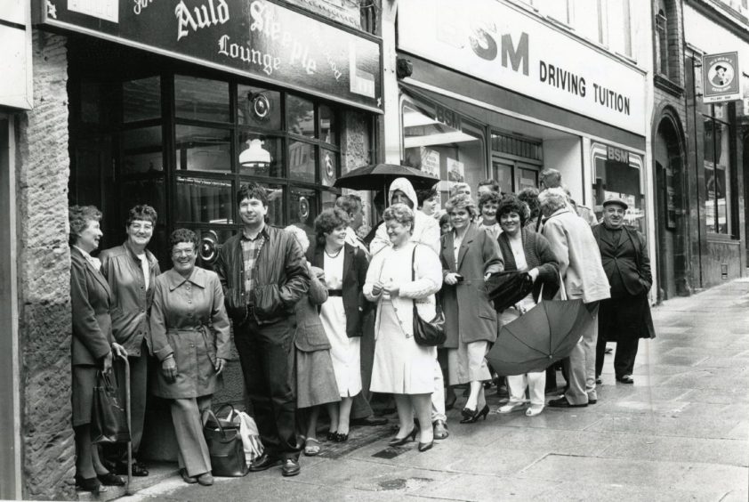 Customers standing in the rain outside the Dundee pub