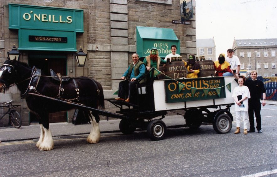 a horse-drawn cart carrying a man dressed as a leprechaun and several beer kegs sits outside Dundee pub O'Neills in 1994