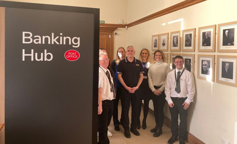 Group of people beside banking hub sign