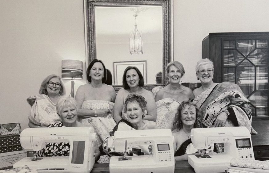 Grup of topless women in front of sewing machines