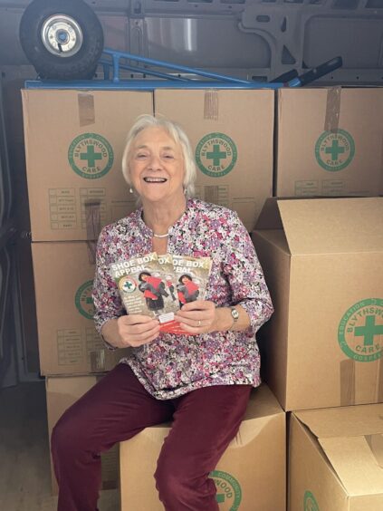 Katie Alstaff, seated in front of a pile of Blythswood Care cardboard boxes