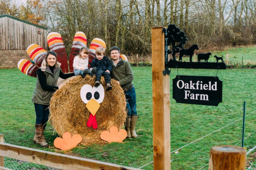 The Sands family of four by a decorated haybale at Oakfield Farm.