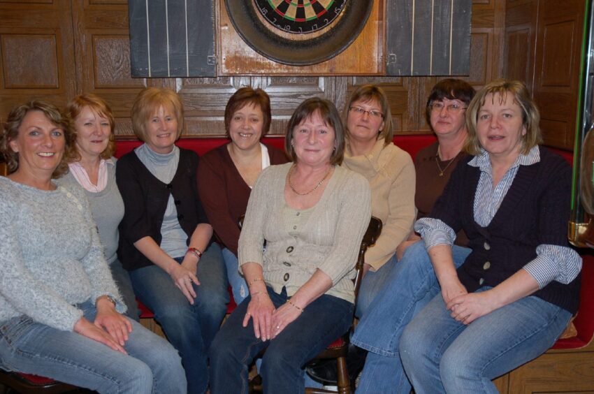 Femaile players from the Tutties Neuk darts team gather round the board. 