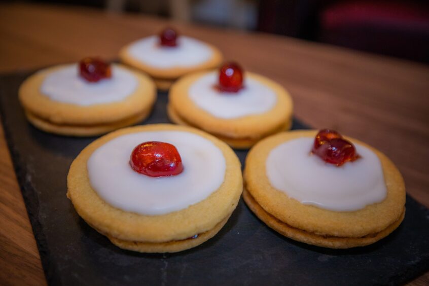 Elizabeth's empire biscuits with white icing and bright red cherries on top.