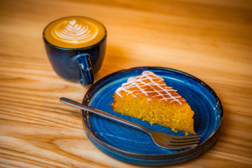 A cup of coffee and a slice of orange polenta cake.