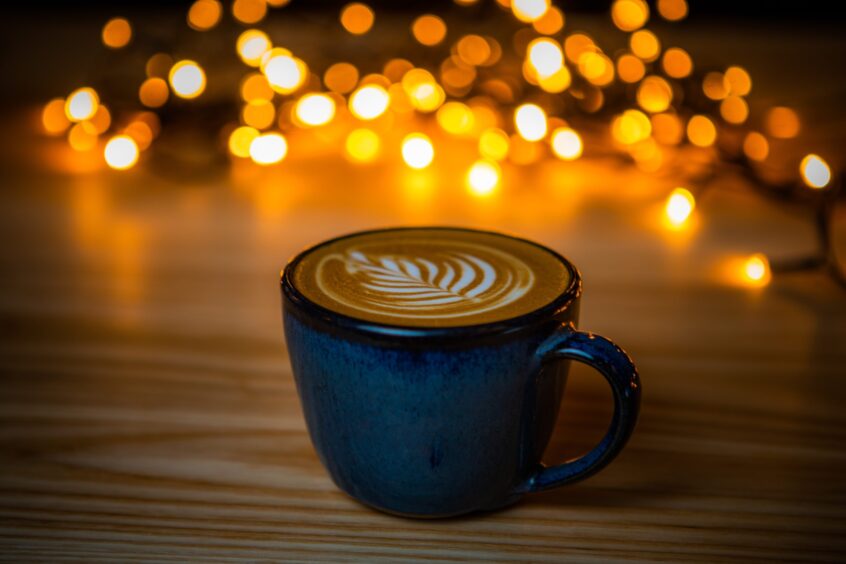 A perfect cup of coffee with fairy lights behind.