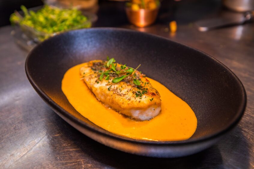 Monkfish tail on top of thermidor sauce in a place oval bowl.