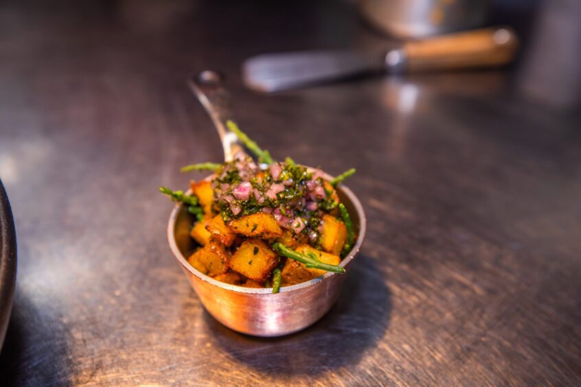 A small dish og=f roasted cubes of potaties mixed with green samphire.