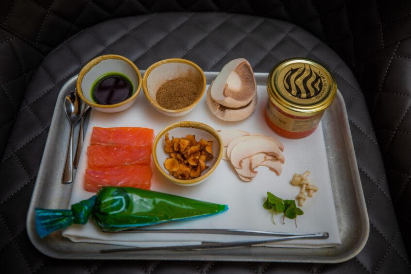 The ingredients for the ranbow trout dish on a tray: cold smoked rainbow trout, a jar of trout caviar, cep powder, pine oil, pine mayonnaise, mushrooms fried Jerusalem artichoke slices and fresh wood sorrel leaves.